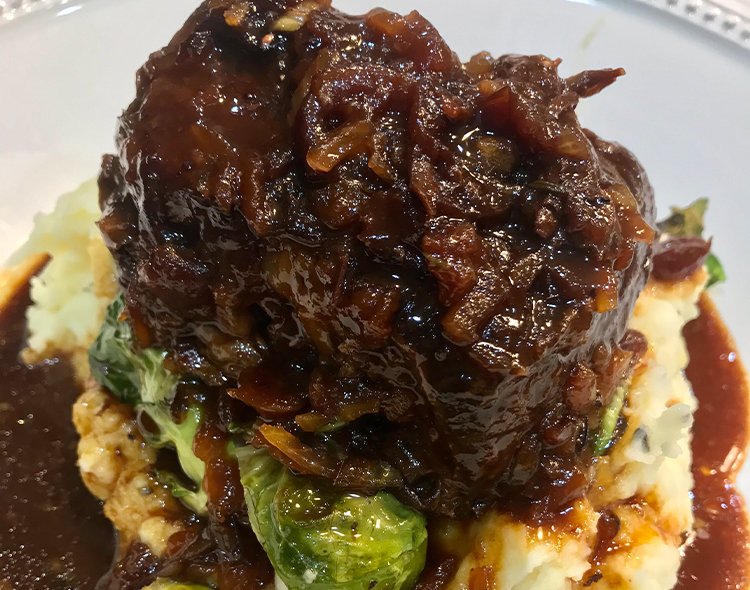 Cranberry-braised beef ribs on a bed of mashed potatoes and Brussel sprouts