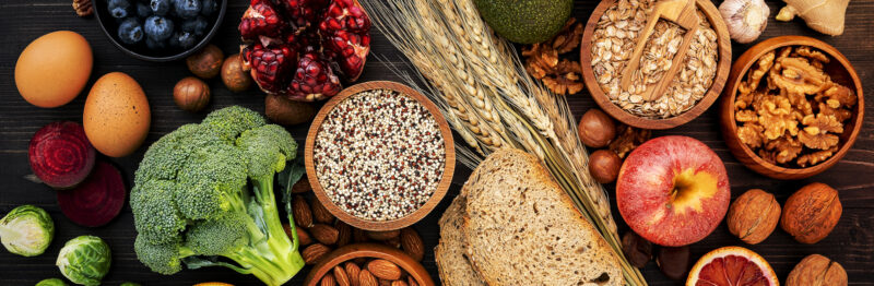 Overhead shot of a variety of ingredients, including quinoa, grains, walnuts, broccoli, eggs, apples blueberries and more