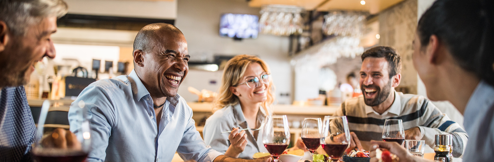 A group of people smiling and laughing while enjoying a meal